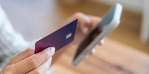Person holding payment card and making purchase on mobile device